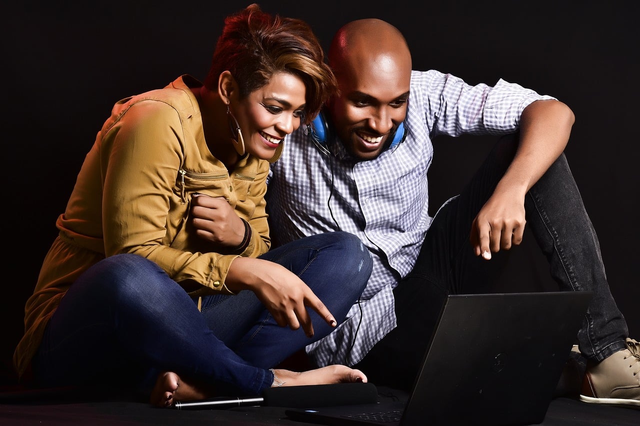 smiling couple viewing laptop